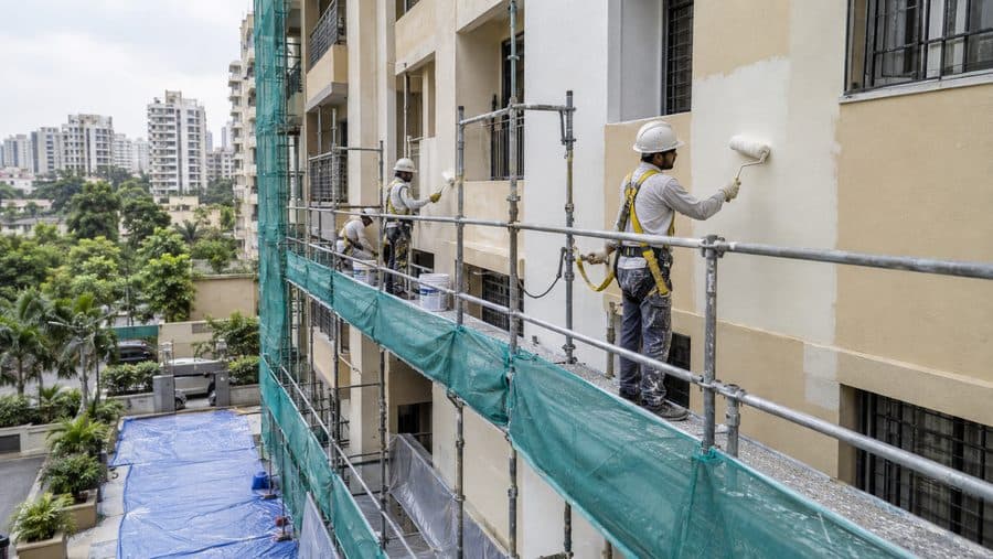 Exterior wall of a house being painted from scaffolding