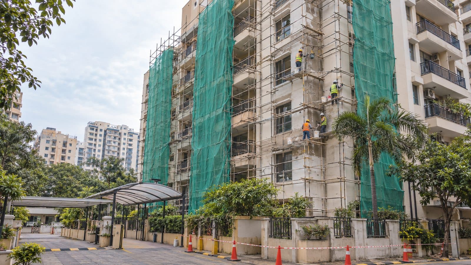 Residential tower wrapped in green safety netting and scaffolding during facade renovation